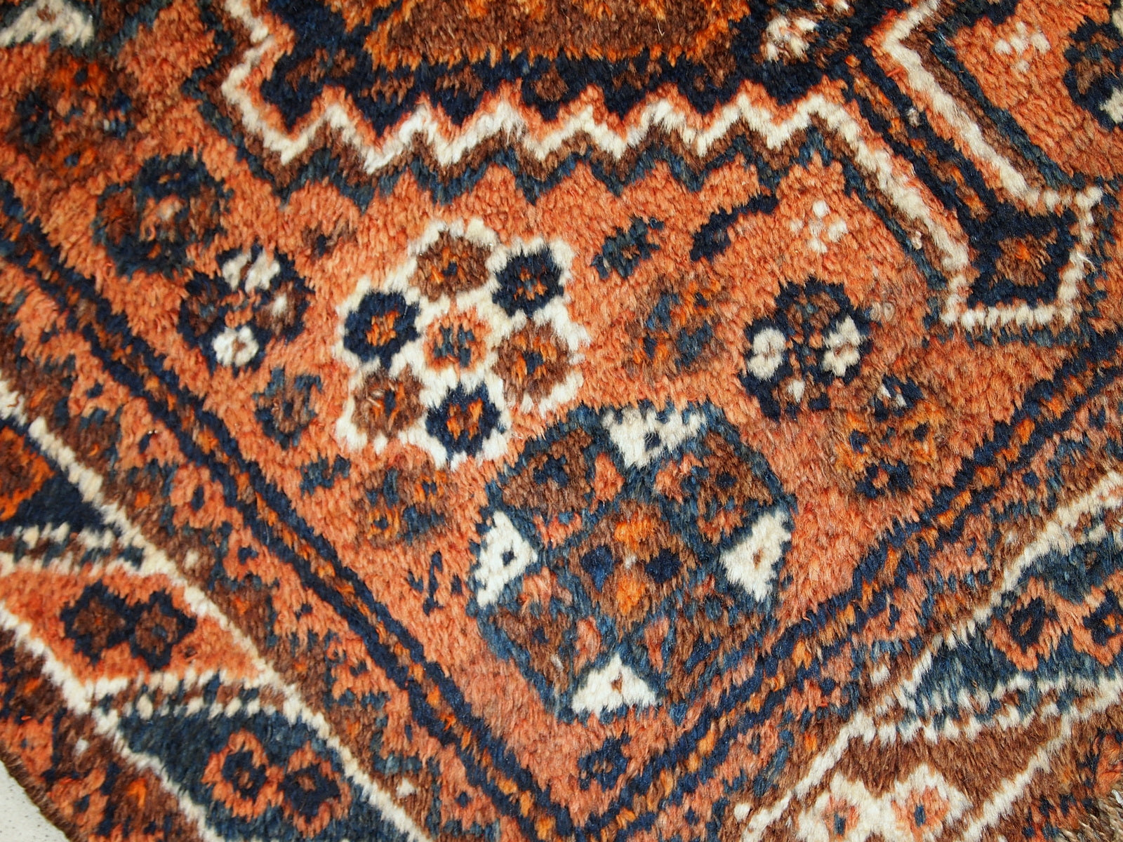 Antique collectible Persian Shiraz rug in original good condition. The rug is in rust shade with navy blue and white details. 