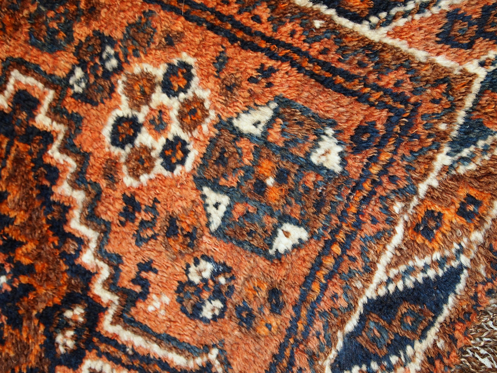 Antique collectible Persian Shiraz rug in original good condition. The rug is in rust shade with navy blue and white details. 
