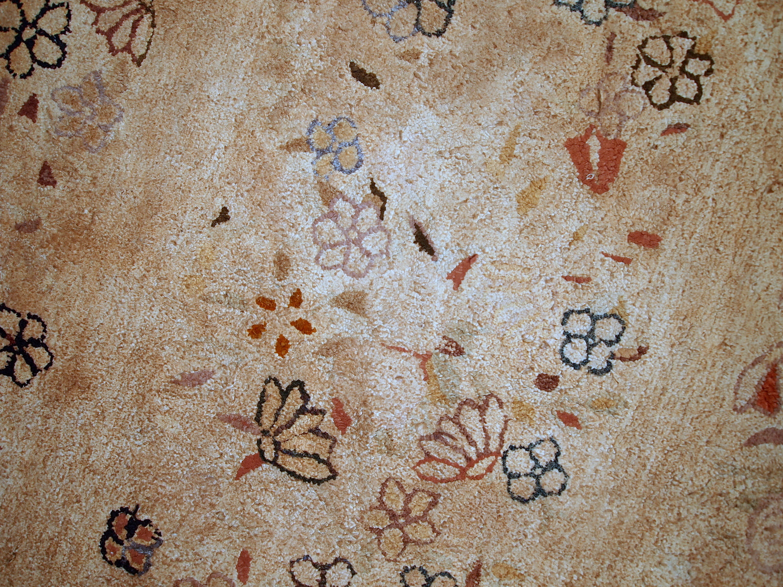 Handmade antique American hooked rug in good condition. Allover design in beige shade with random floral decorations on it. The rug is from the end of 19th century and made in wool.