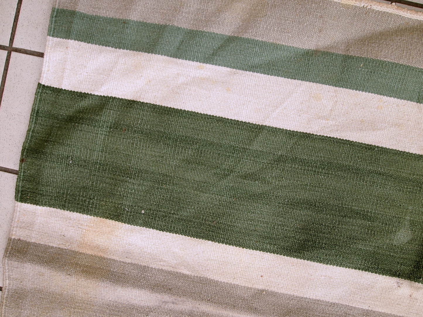 This kilim has very simple stripes motive in dark green, white and grey shades. It is in original condition from the beginning of 20th century, has some stains.