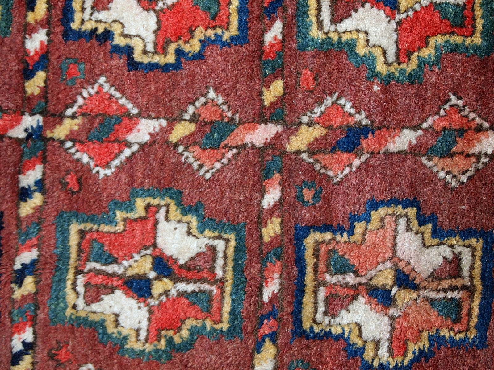 This antique Kurdish rug made in deep shade of burgundy. All-over design with geometric and tribal accents. The wool on the rug is soft, it is in original good condition.