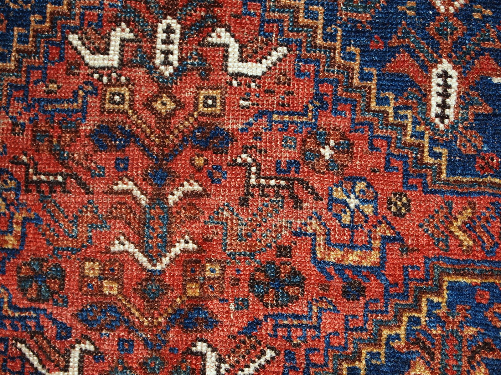 Handmade antique Khamseh rug from the beginning of 20th century with symmetric design and deep shades. The rug has some low pile.