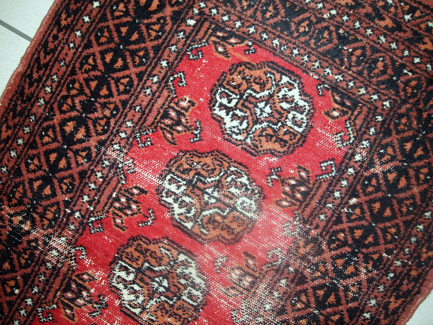 Vintage rug from Pakistan in distressed condition. The rug made in the end of 20th century in red wool.