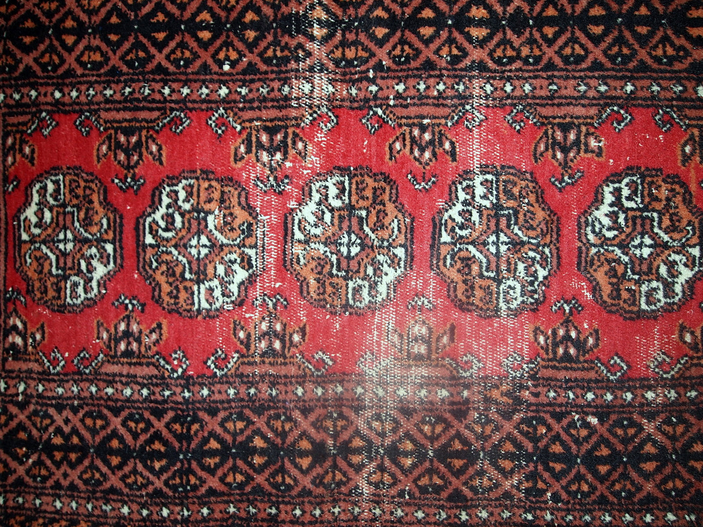 Vintage rug from Pakistan in distressed condition. The rug made in the end of 20th century in red wool.