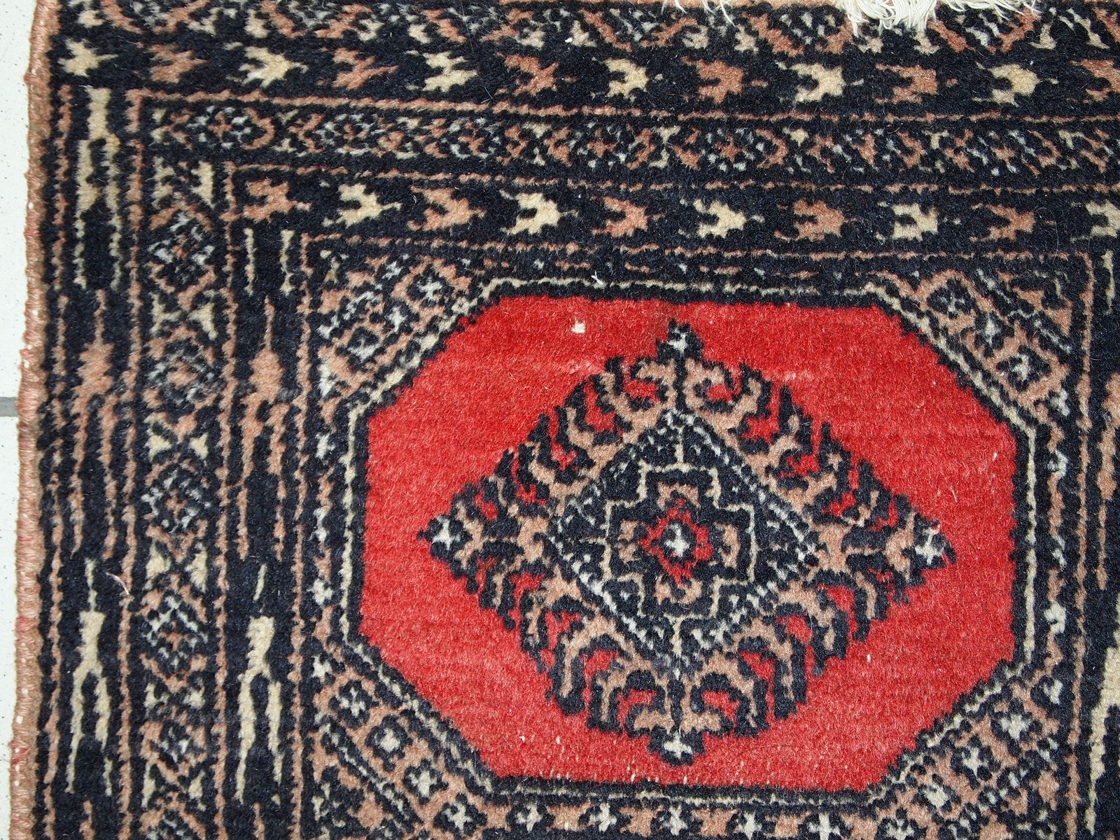 Vintage rug from Pakistan in distressed condition. The rug made in the end of 20th century in red wool.