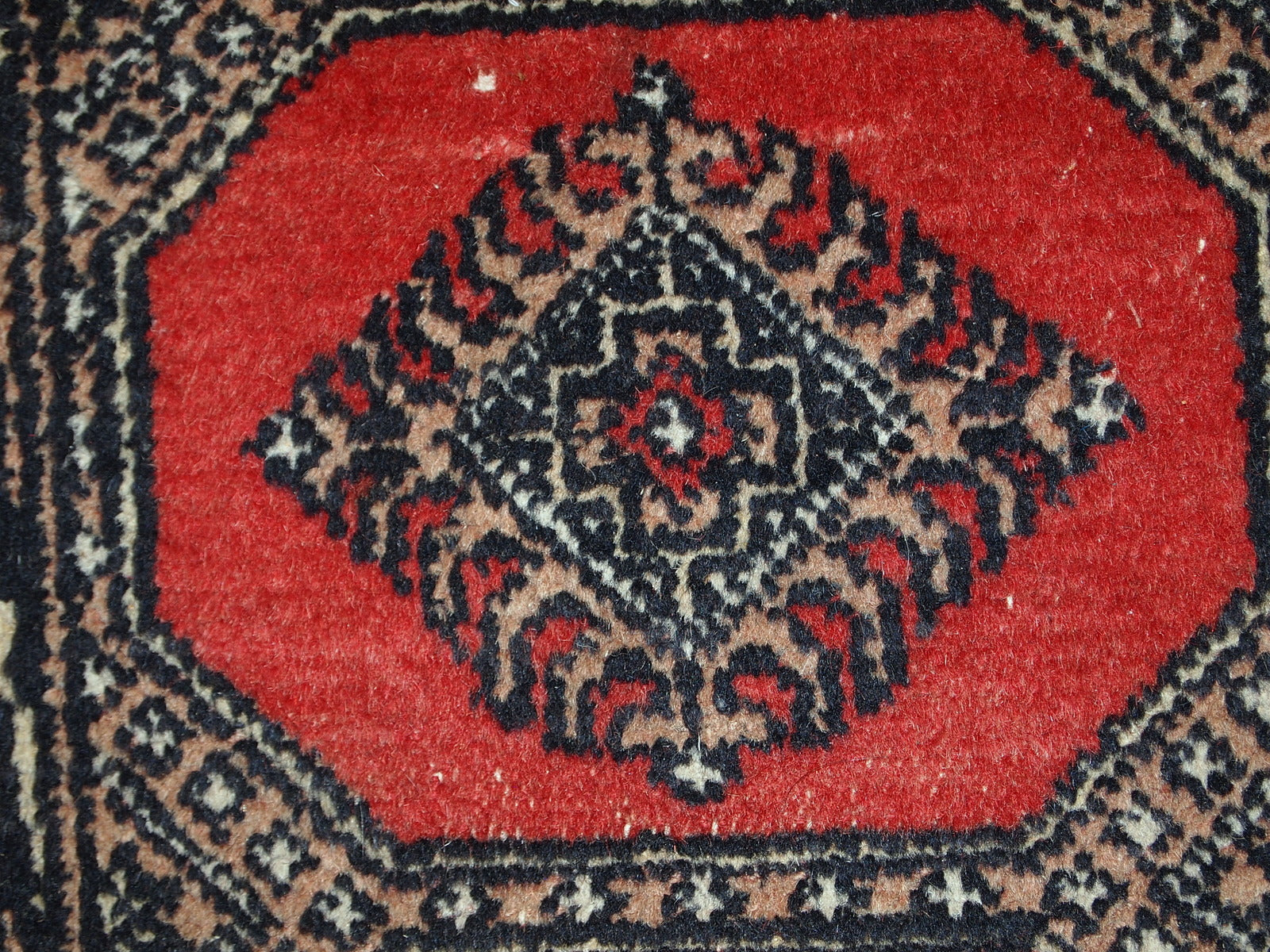 Vintage rug from Pakistan in distressed condition. The rug made in the end of 20th century in red wool.