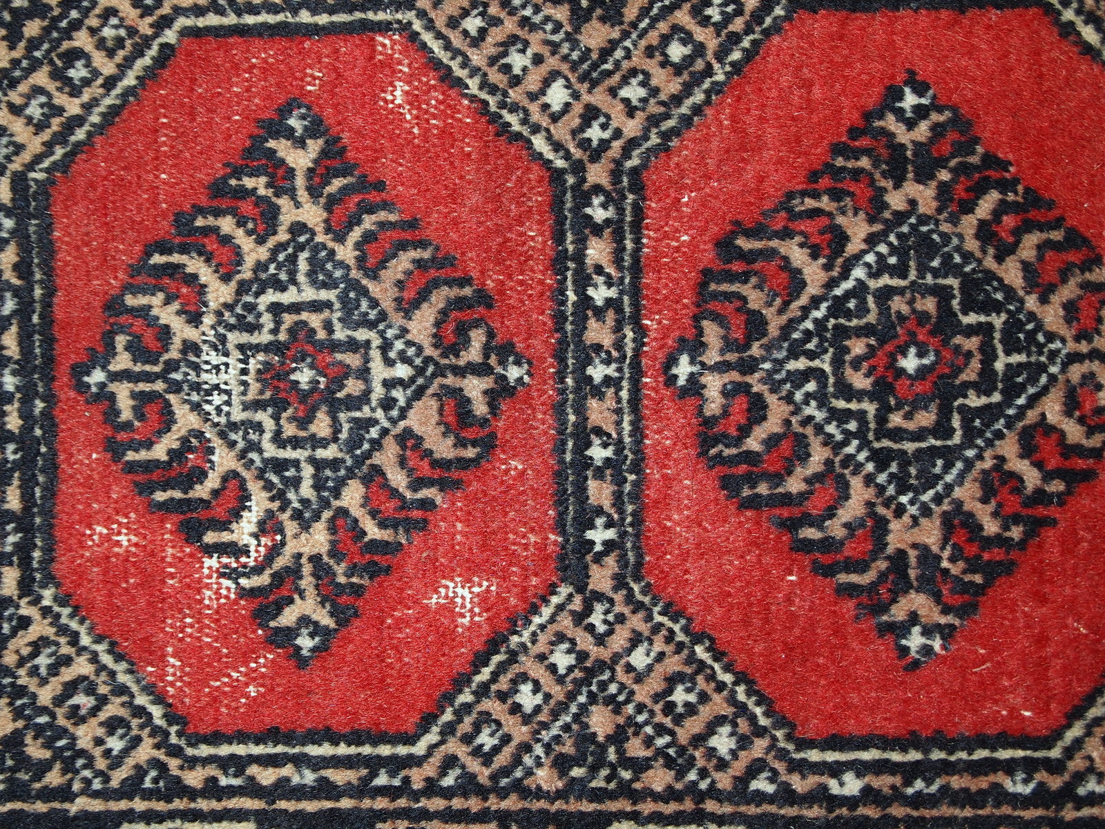 Vintage rug from Pakistan in distressed condition. The rug made in the end of 20th century in red wool.