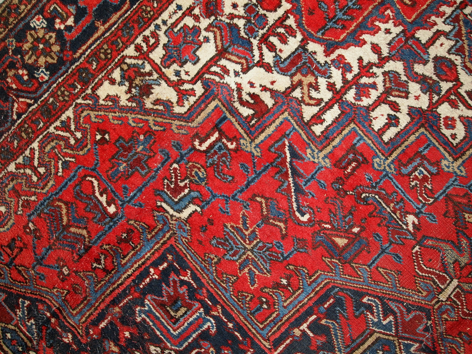 Handmade antique Persian Heriz rug from the middle of 20th century. The rug is in original condition, it has some low pile.