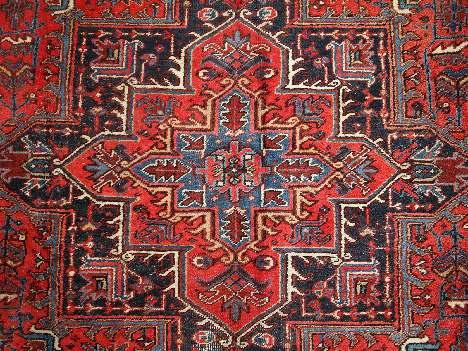 Handmade antique Persian Heriz rug from the middle of 20th century. The rug is in original condition, it has some low pile.