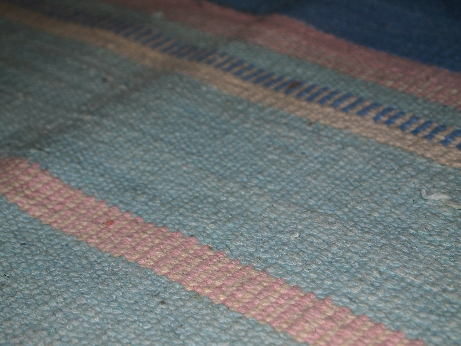 Close-up view of the kilim's pastel sea blue and beige stripes.