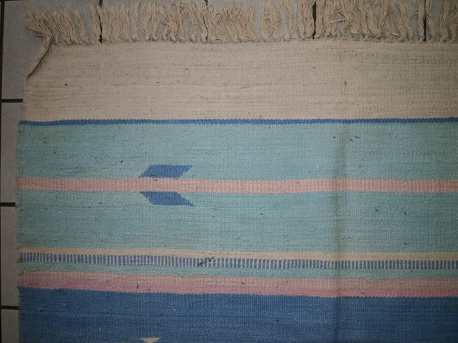 Close-up view of the kilim's tribal pattern with beige and sky blue stripes.