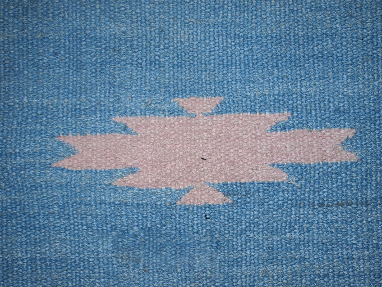 Detail shot of the kilim's tribal design with pink and beige accents.