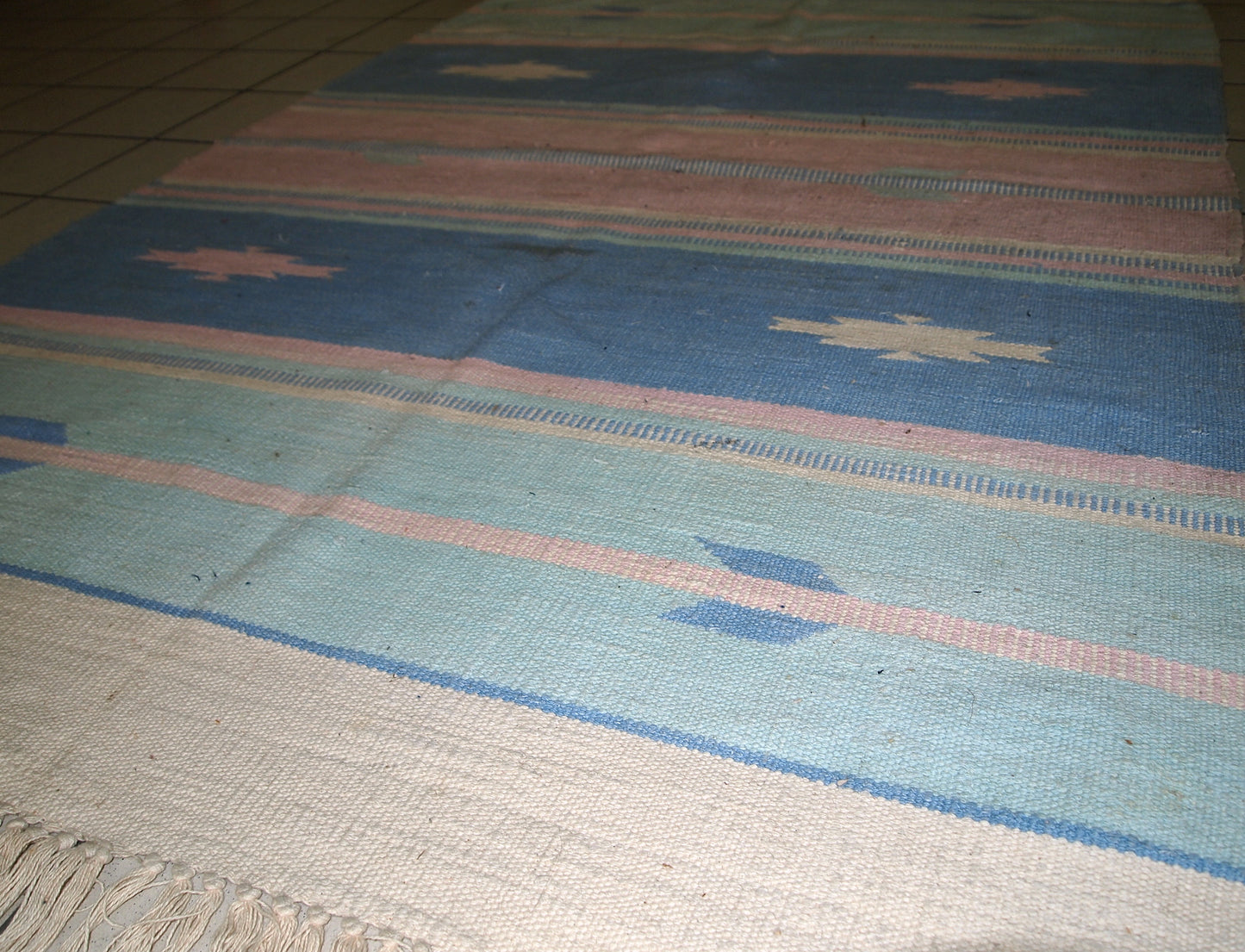 Close-up view of the kilim's tribal pattern and pastel stripes.