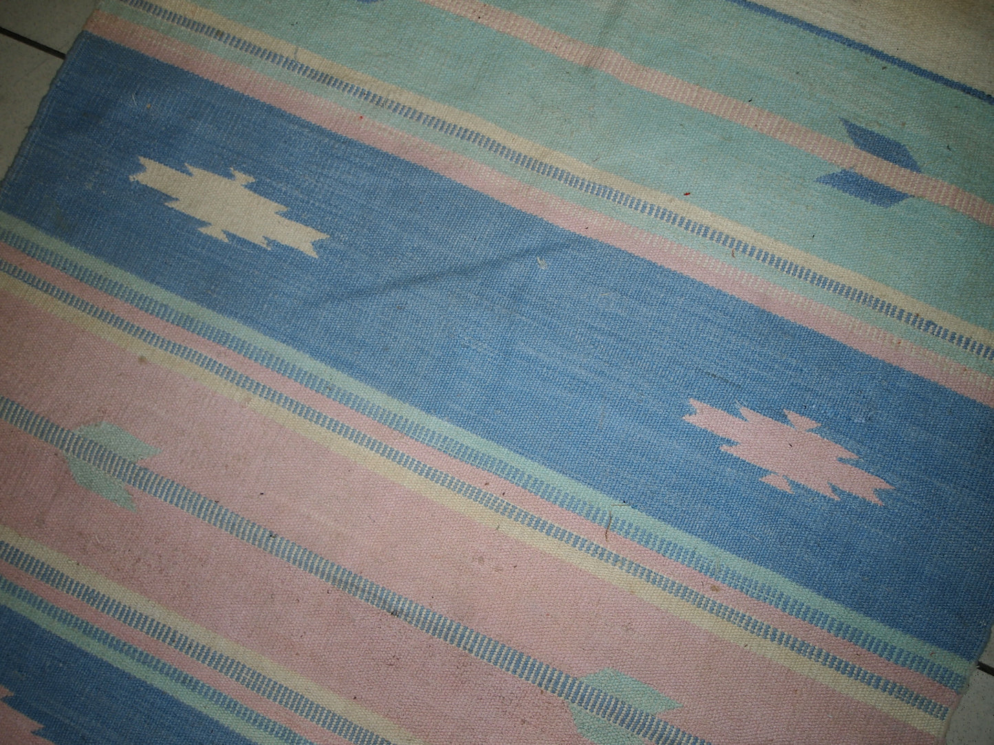 Close-up view of the kilim's intricate tribal motif in soft pastel pink.