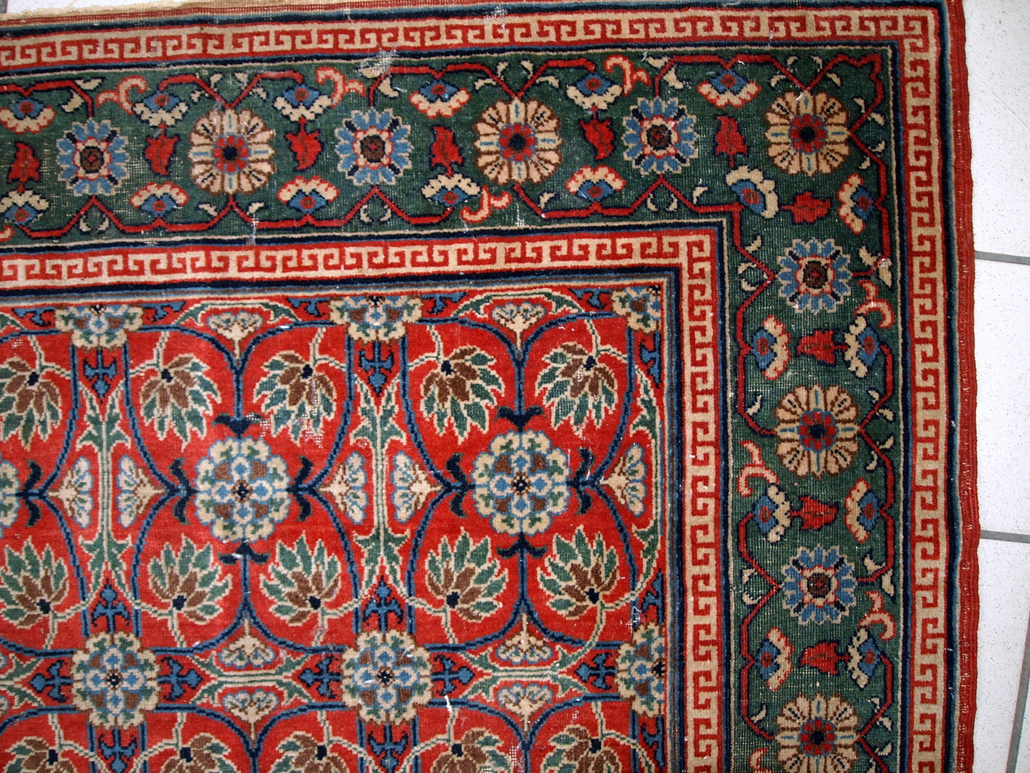 Handmade antique East Turkestan distressed rug with repeating pattern. It is in red and green shades, made in the beginning of 20th century.