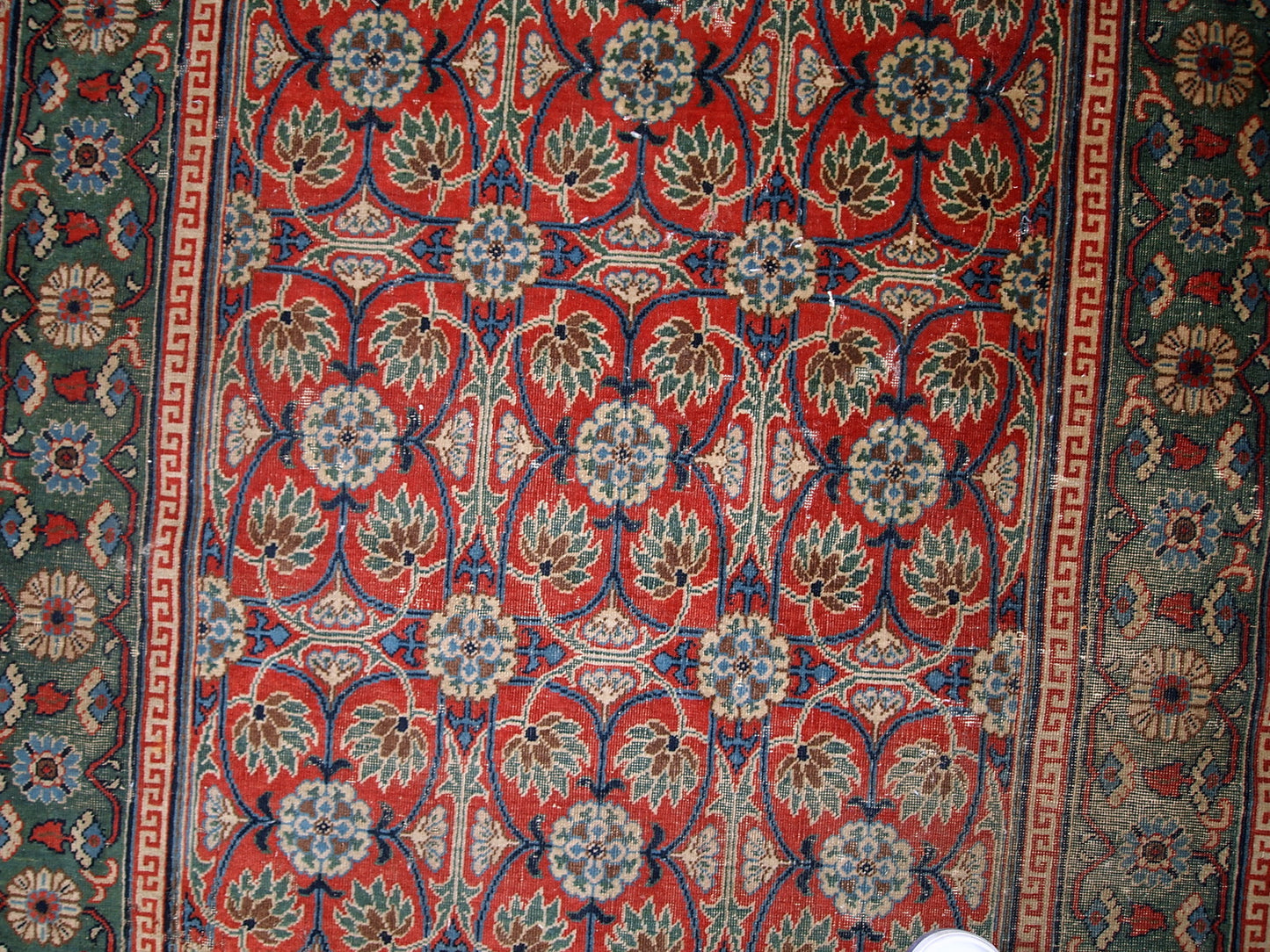 Handmade antique East Turkestan distressed rug with repeating pattern. It is in red and green shades, made in the beginning of 20th century.