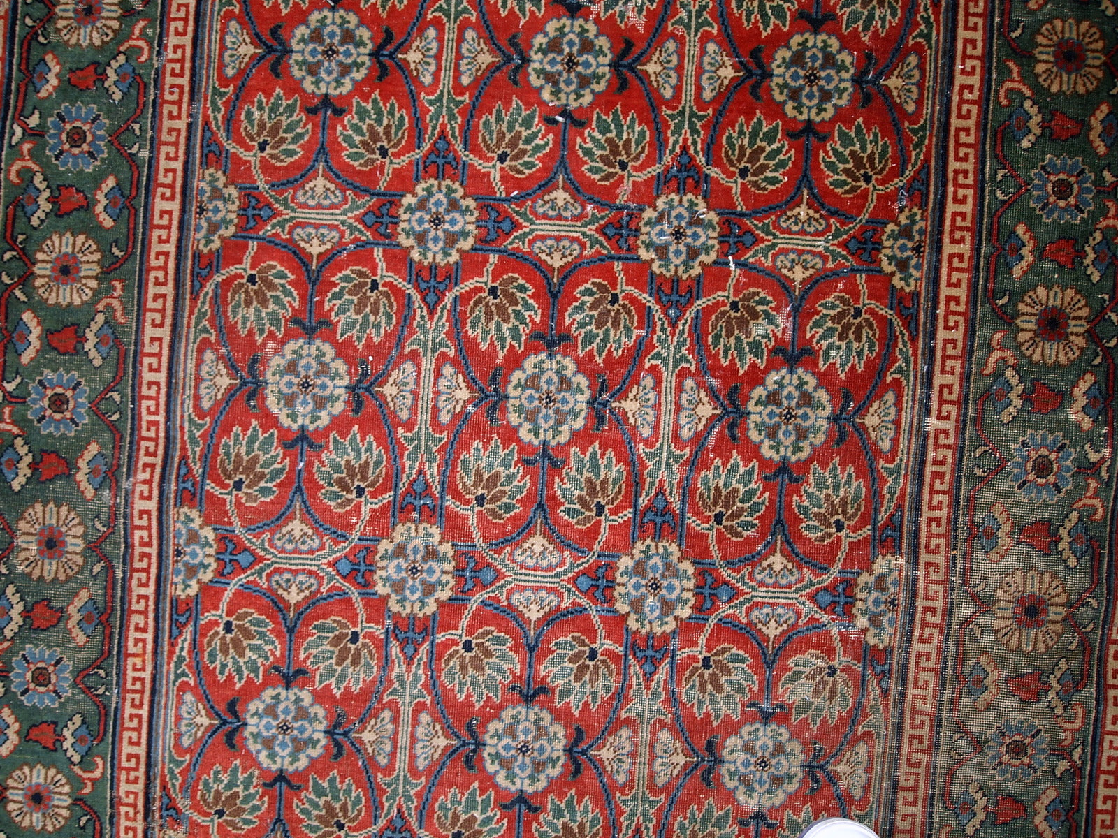 Handmade antique East Turkestan distressed rug with repeating pattern. It is in red and green shades, made in the beginning of 20th century.