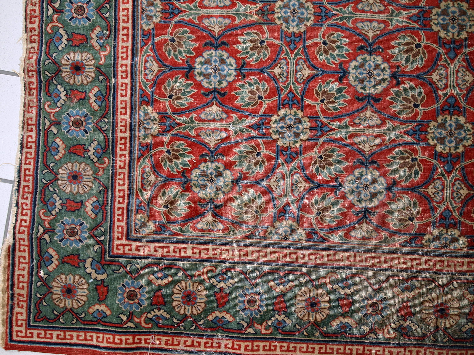 Handmade antique East Turkestan distressed rug with repeating pattern. It is in red and green shades, made in the beginning of 20th century.