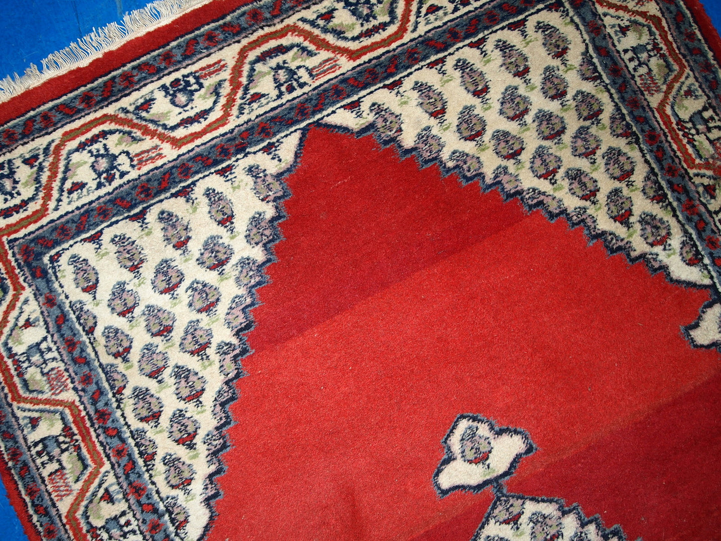 Vintage handmade Indian rug from the end of 20th century. The rug is in original good condition in red and beige wool.