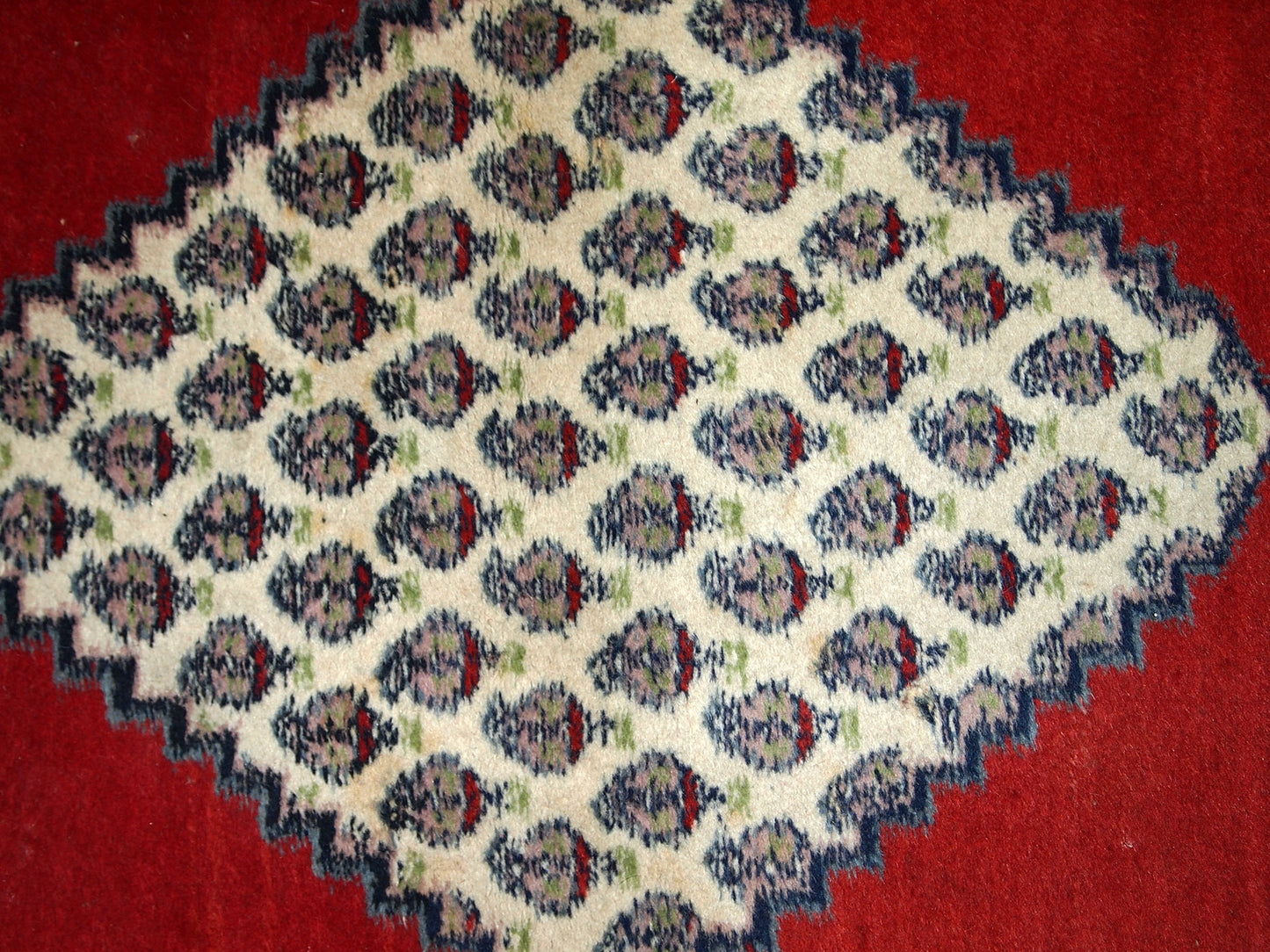 Vintage handmade Indian rug from the end of 20th century. The rug is in original good condition in red and beige wool.