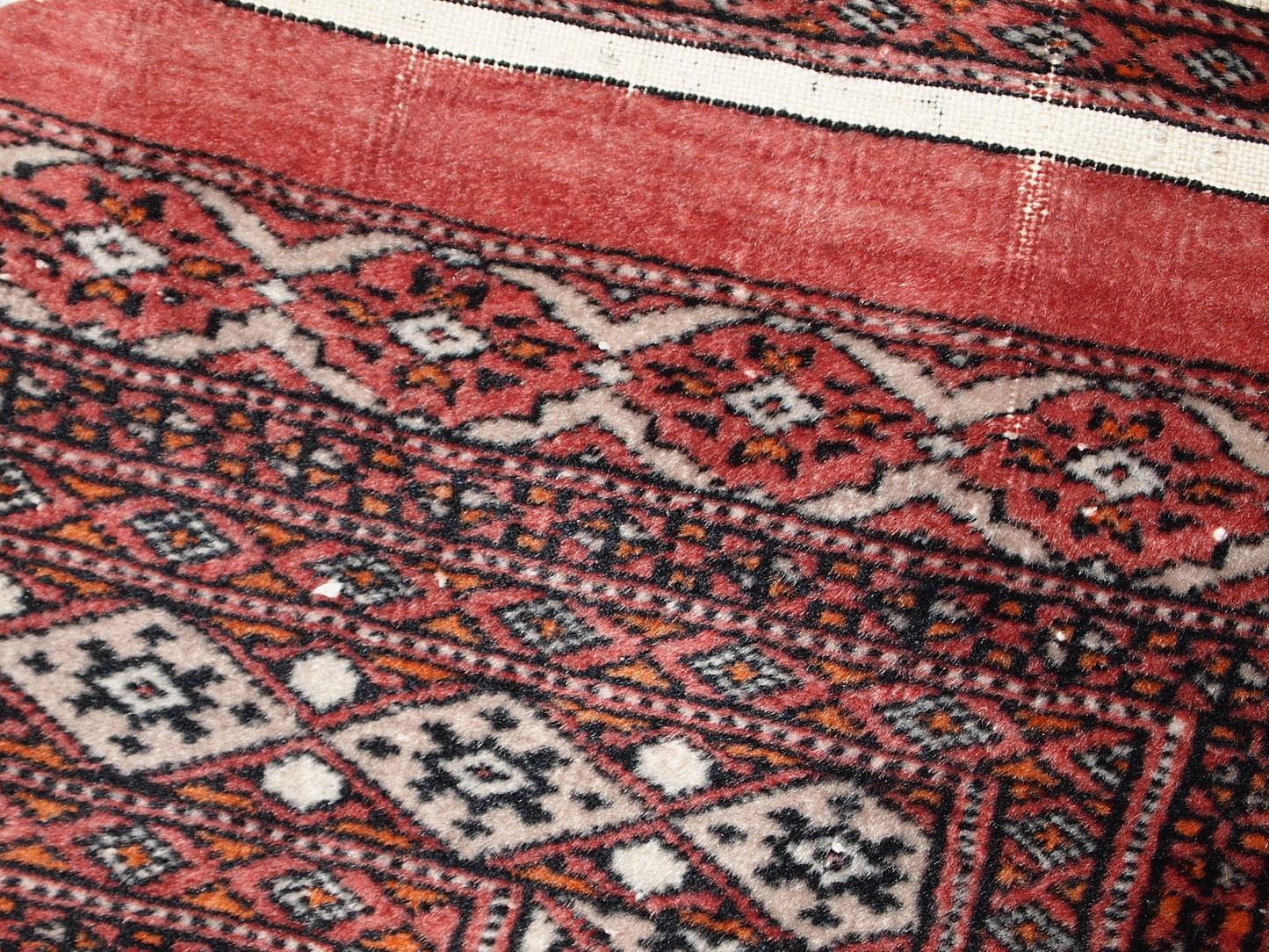 Handmade vintage Uzbek Bukhara distressed rug in traditional design. The rug is from the end of 20th century, it has some low pile.