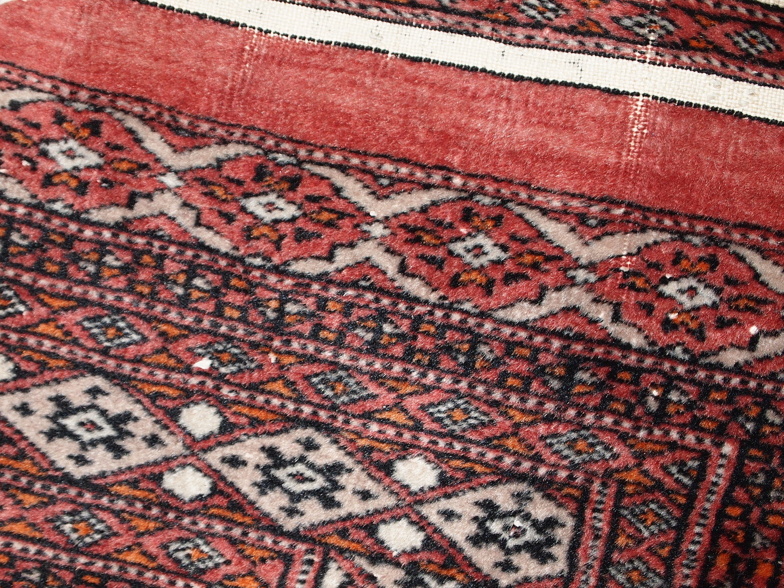 Handmade vintage Uzbek Bukhara distressed rug in traditional design. The rug is from the end of 20th century, it has some low pile.