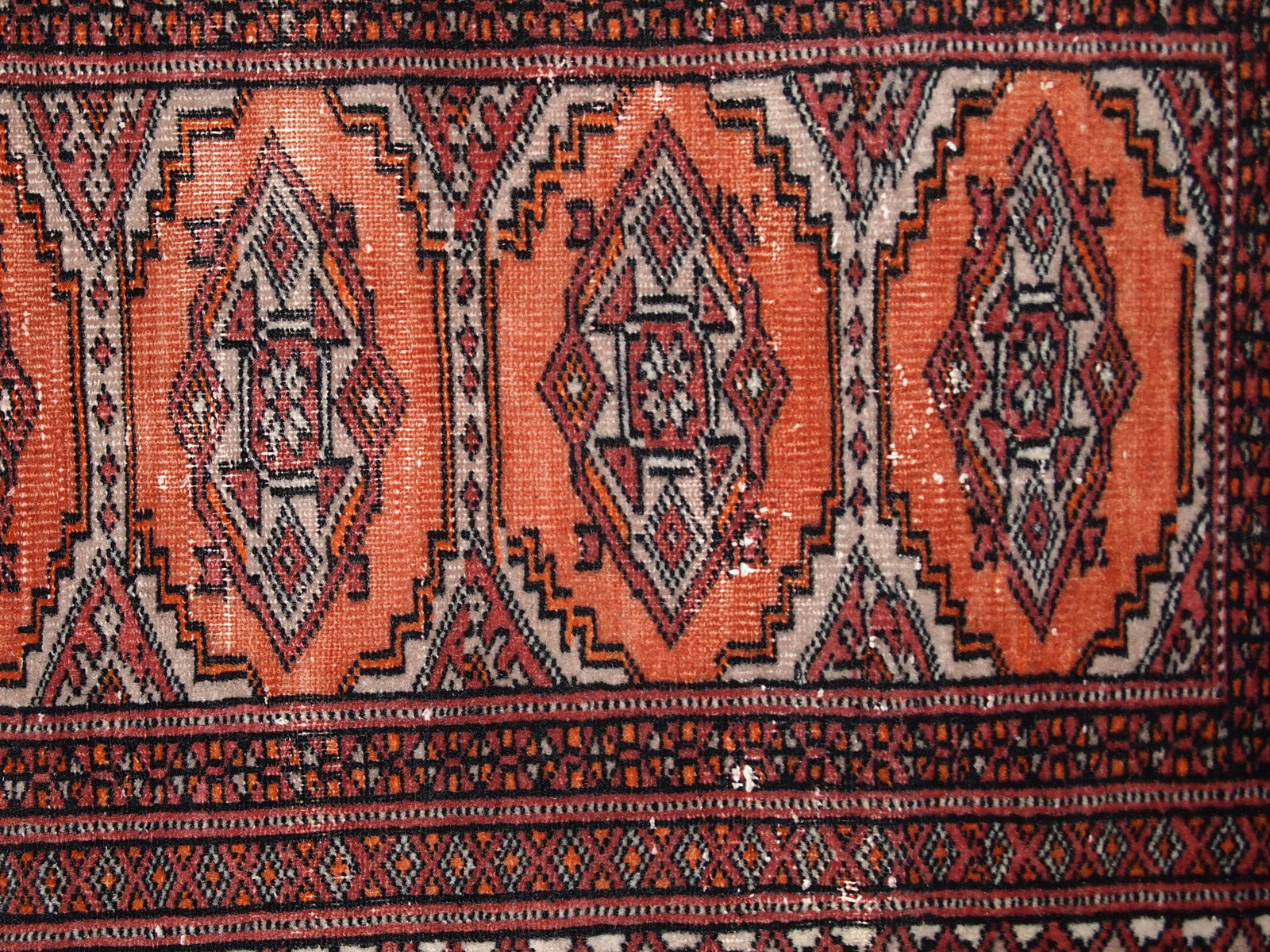 Handmade vintage Uzbek Bukhara distressed rug in traditional design. The rug is from the end of 20th century, it has some low pile.