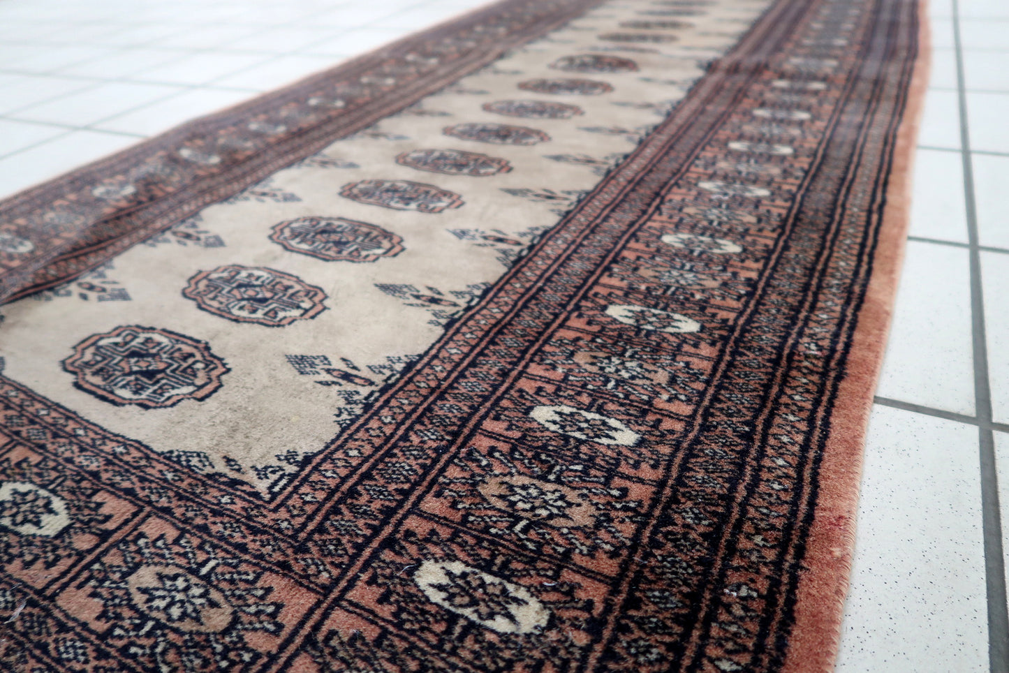 Handmade vintage Uzbek Bukhara distressed runner in traditional design. The rug is from the end of 20th century made in wool.