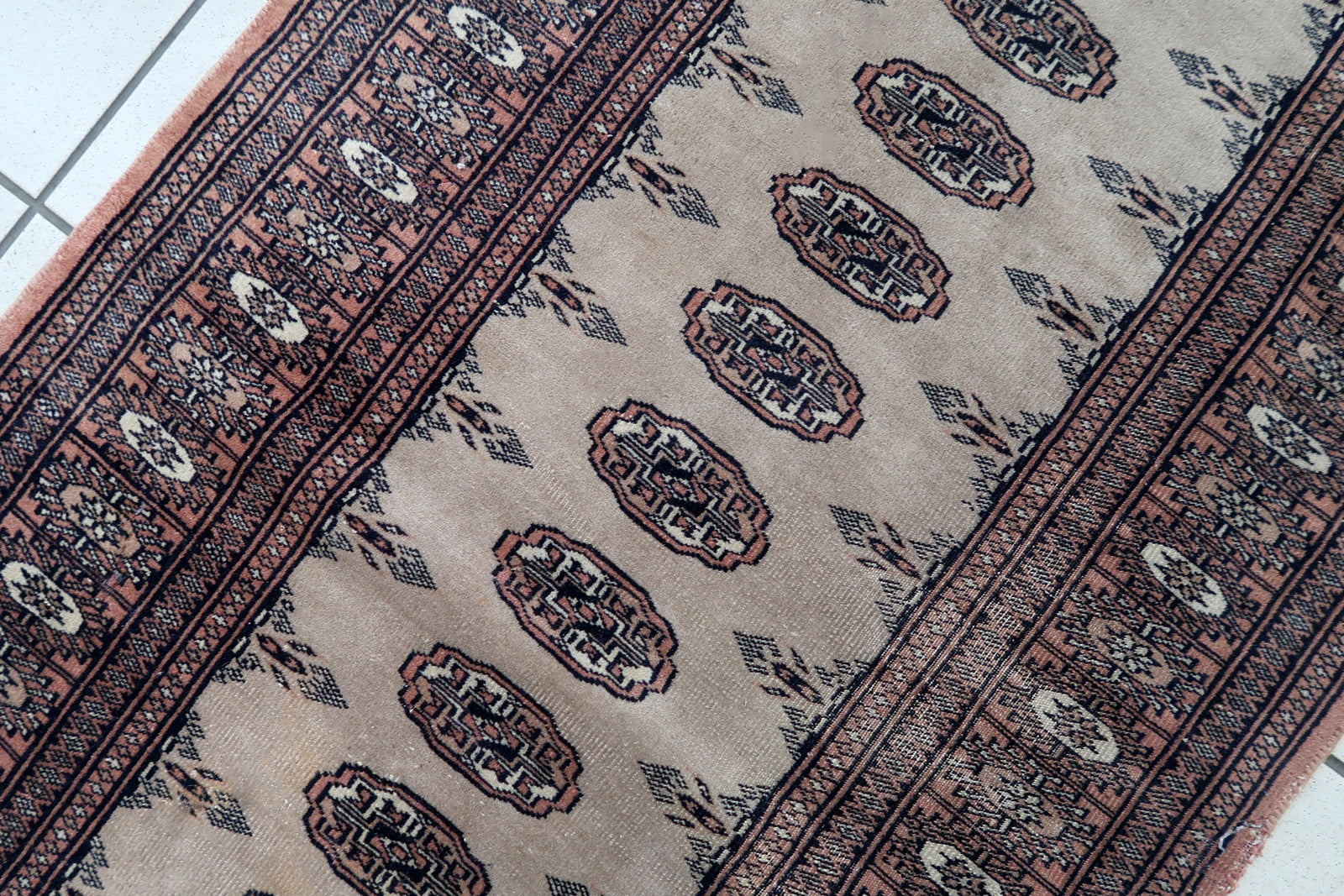 Handmade vintage Uzbek Bukhara distressed runner in traditional design. The rug is from the end of 20th century made in wool.