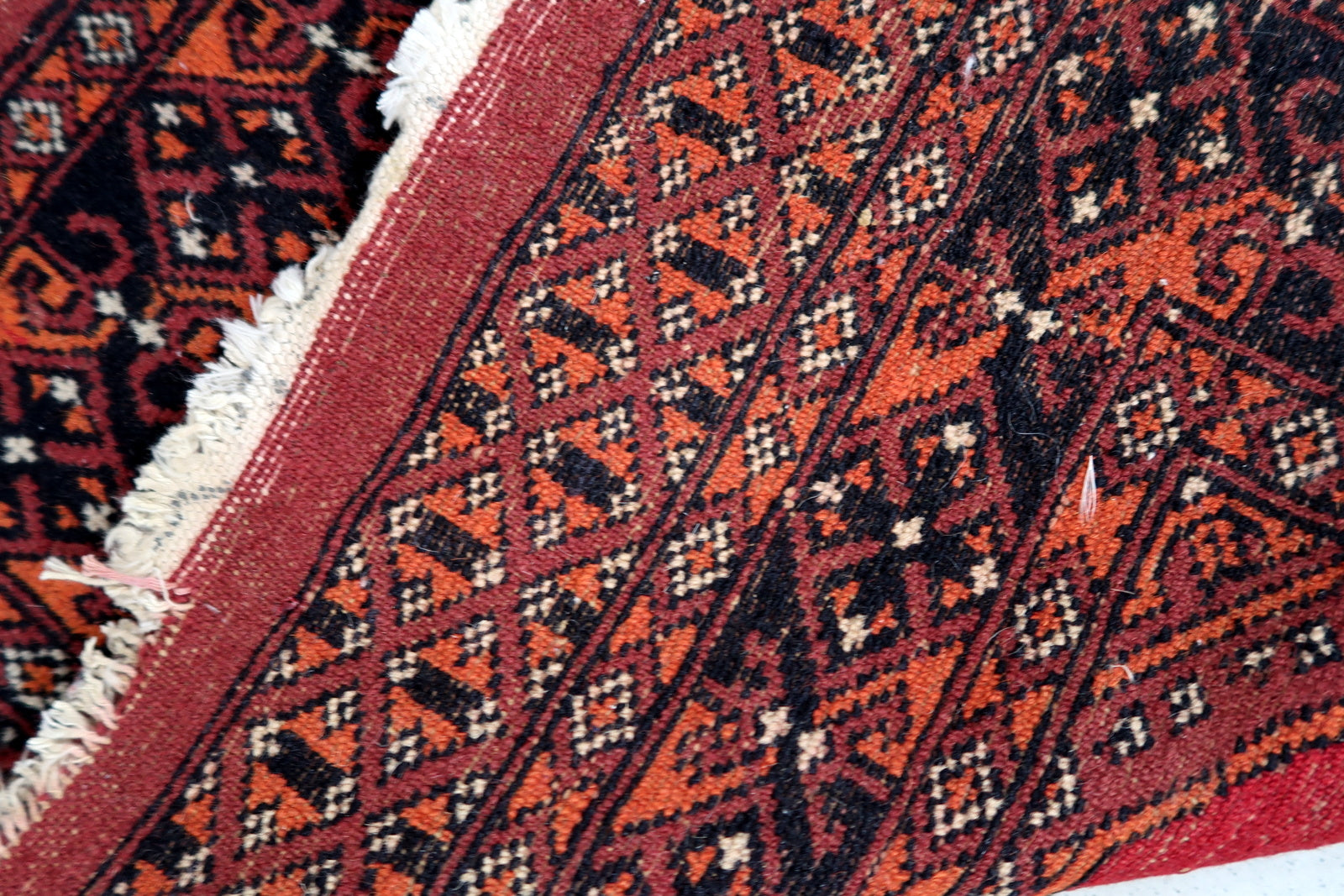 Handmade vintage Uzbek Bukhara rug in traditional design. The rug is from the end of 20th century made in wool. The rug is in original good condition, one corner has been damaged.