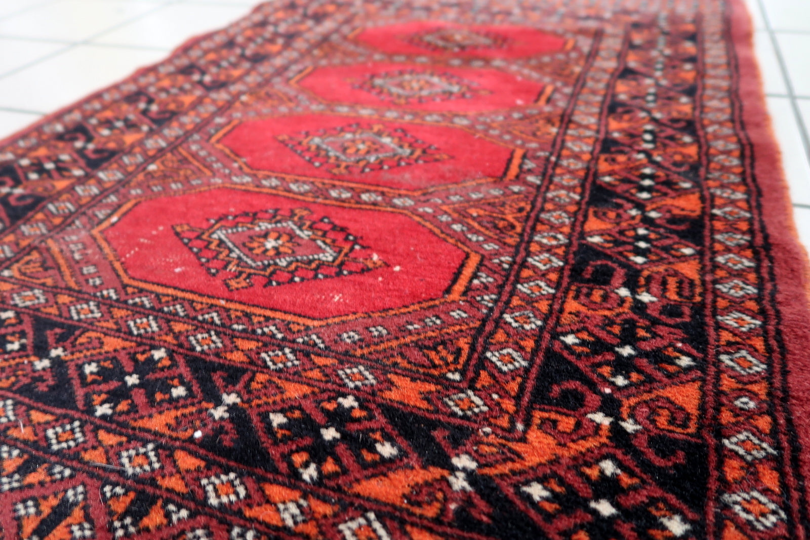 Handmade vintage Uzbek Bukhara rug in traditional design. The rug is from the end of 20th century made in wool. The rug is in original good condition, one corner has been damaged.