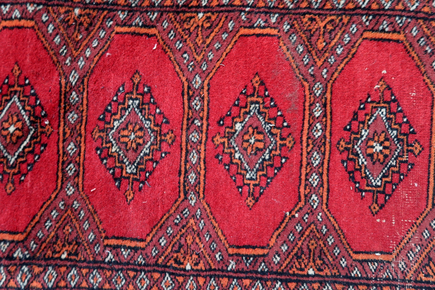 Handmade vintage Uzbek Bukhara rug in traditional design. The rug is from the end of 20th century made in wool. The rug is in original good condition, one corner has been damaged.