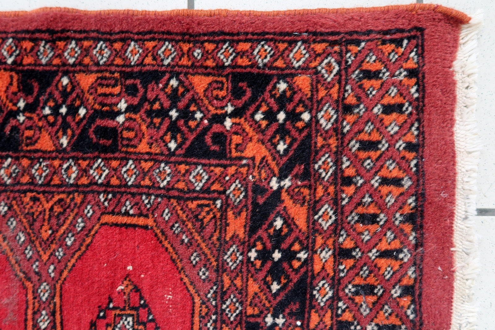 Handmade vintage Uzbek Bukhara rug in traditional design. The rug is from the end of 20th century made in wool. The rug is in original good condition, one corner has been damaged.