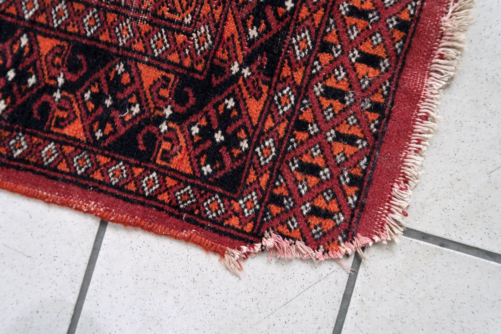 Handmade vintage Uzbek Bukhara rug in traditional design. The rug is from the end of 20th century made in wool. The rug is in original good condition, one corner has been damaged.