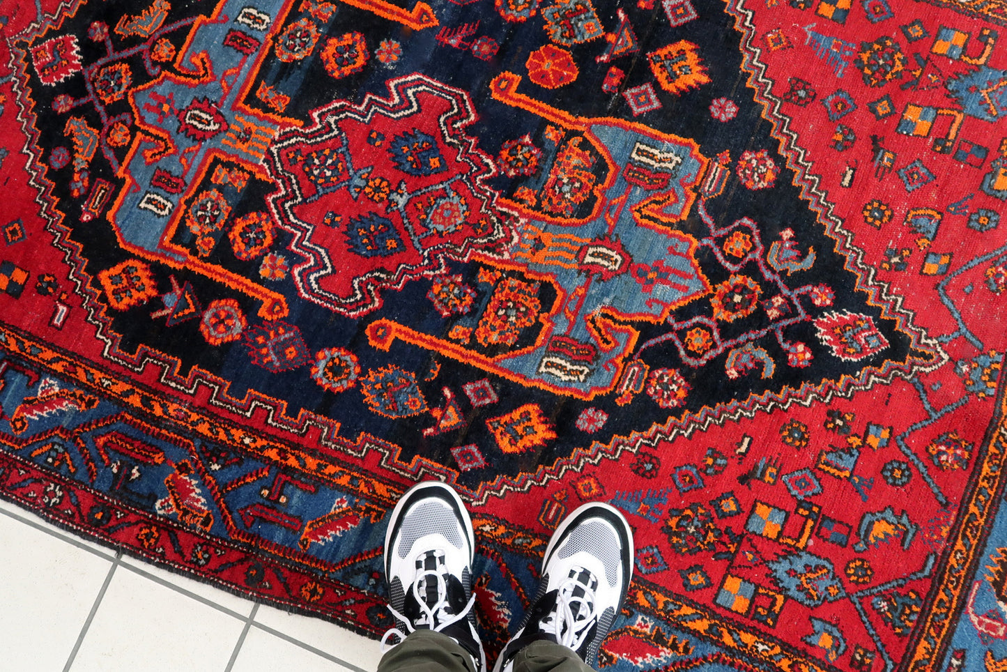 Handmade vintage Middle Eastern rug in red and blue shades. The rug has been made in wool in the middle of 20th century. It is in original condition, it has some low pile. The design on the rug is unusual, medallion is not even.