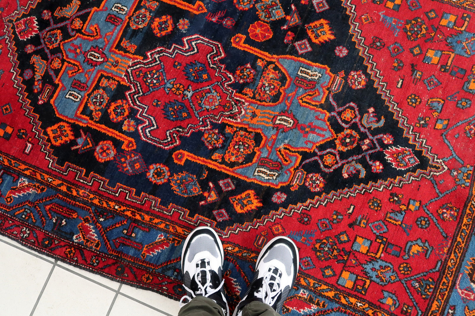 Handmade vintage Middle Eastern rug in red and blue shades. The rug has been made in wool in the middle of 20th century. It is in original condition, it has some low pile. The design on the rug is unusual, medallion is not even.