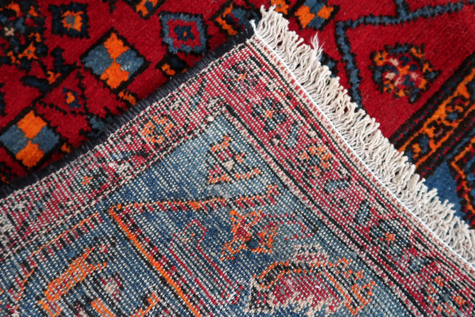 Handmade vintage Middle Eastern rug in red and blue shades. The rug has been made in wool in the middle of 20th century. It is in original condition, it has some low pile. The design on the rug is unusual, medallion is not even.