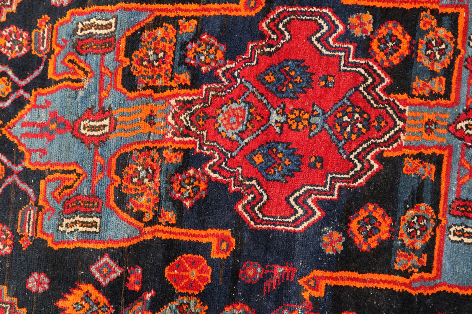 Handmade vintage Middle Eastern rug in red and blue shades. The rug has been made in wool in the middle of 20th century. It is in original condition, it has some low pile. The design on the rug is unusual, medallion is not even.