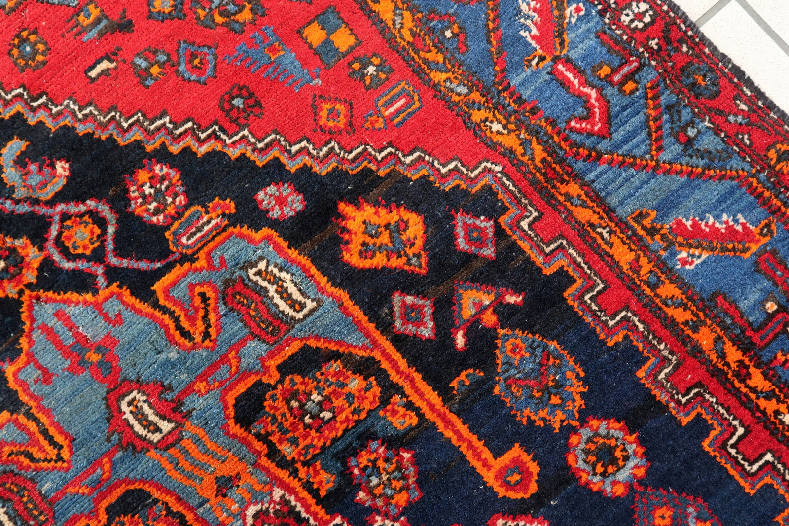 Handmade vintage Middle Eastern rug in red and blue shades. The rug has been made in wool in the middle of 20th century. It is in original condition, it has some low pile. The design on the rug is unusual, medallion is not even.