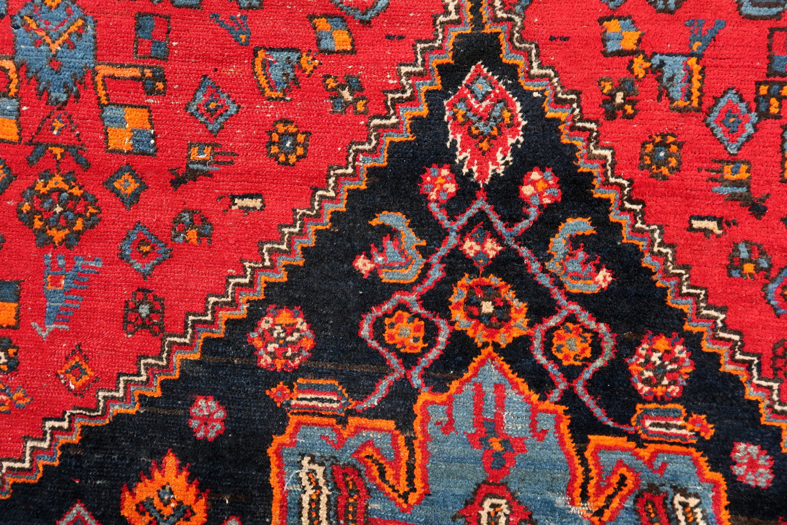 Handmade vintage Middle Eastern rug in red and blue shades. The rug has been made in wool in the middle of 20th century. It is in original condition, it has some low pile. The design on the rug is unusual, medallion is not even.
