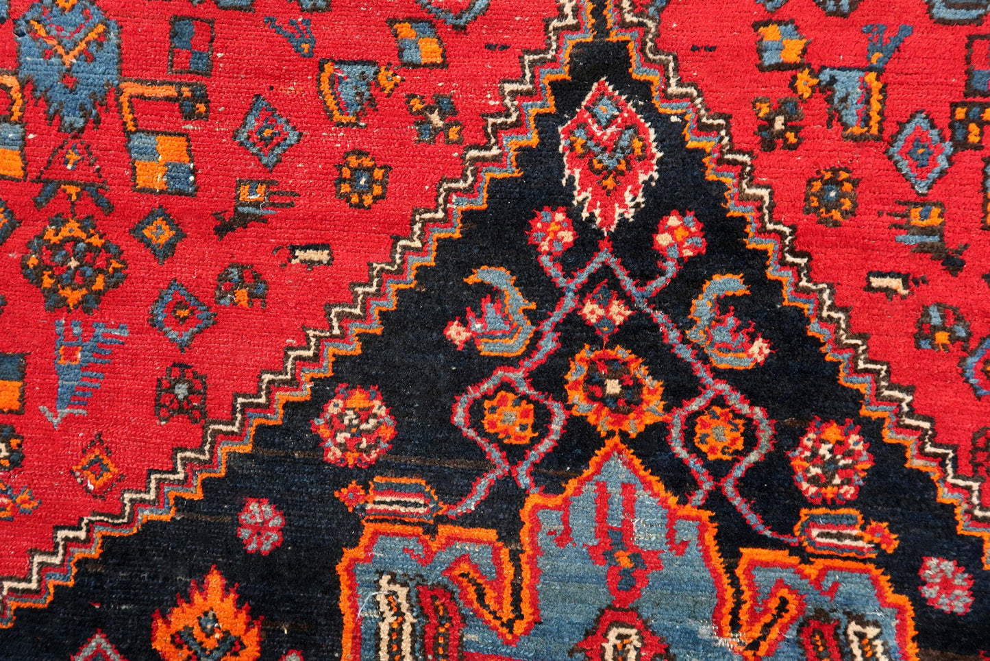 Handmade vintage Middle Eastern rug in red and blue shades. The rug has been made in wool in the middle of 20th century. It is in original condition, it has some low pile. The design on the rug is unusual, medallion is not even.