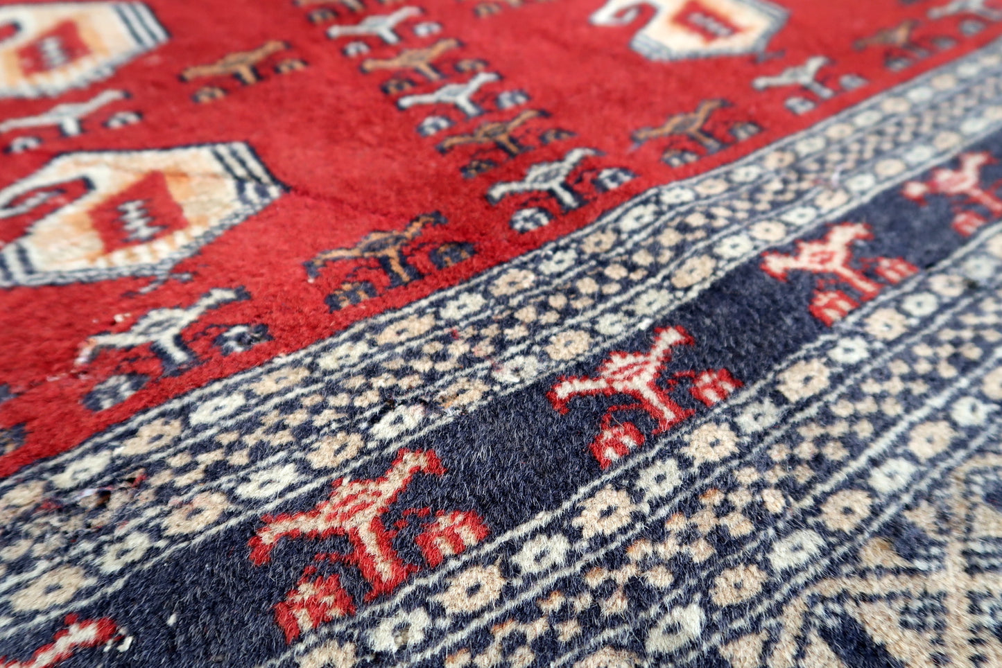Handmade vintage Uzbek Bukhara rug in red color. The rug has been made in wool in the middle of 20th century. It is in original condition, it has some low pile.