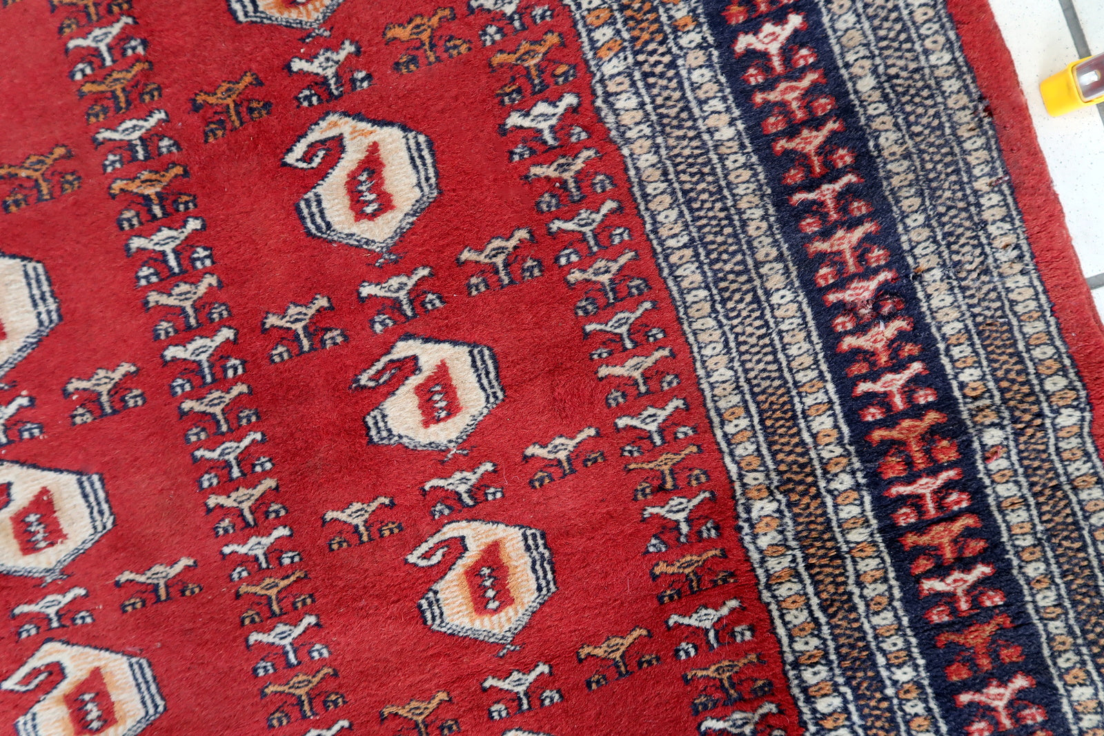 Handmade vintage Uzbek Bukhara rug in red color. The rug has been made in wool in the middle of 20th century. It is in original condition, it has some low pile.