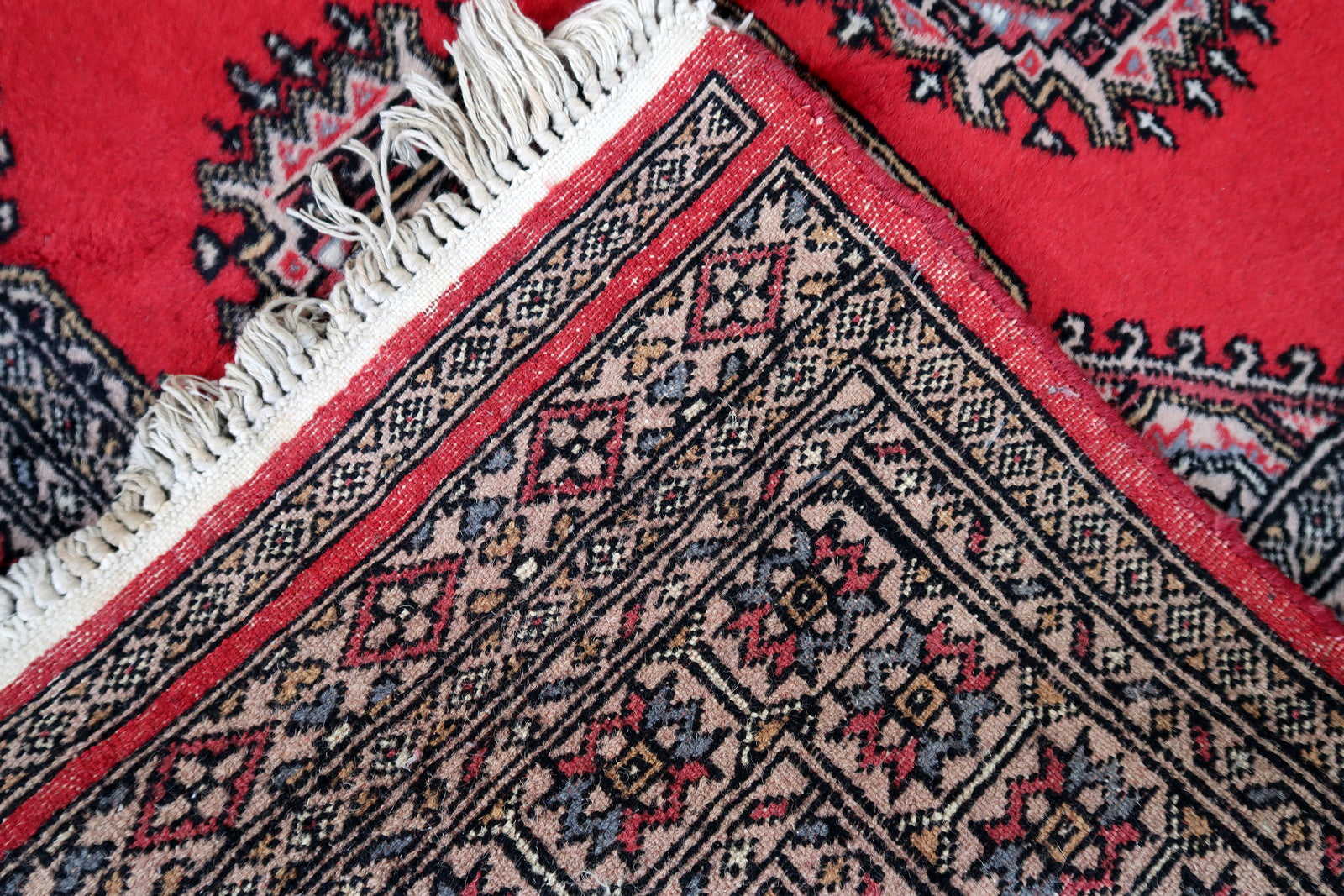 Handmade vintage Uzbek Bukhara rug in red color. The rug has been made in wool in the end of 20th century. It is in original condition, it has some signs of age.