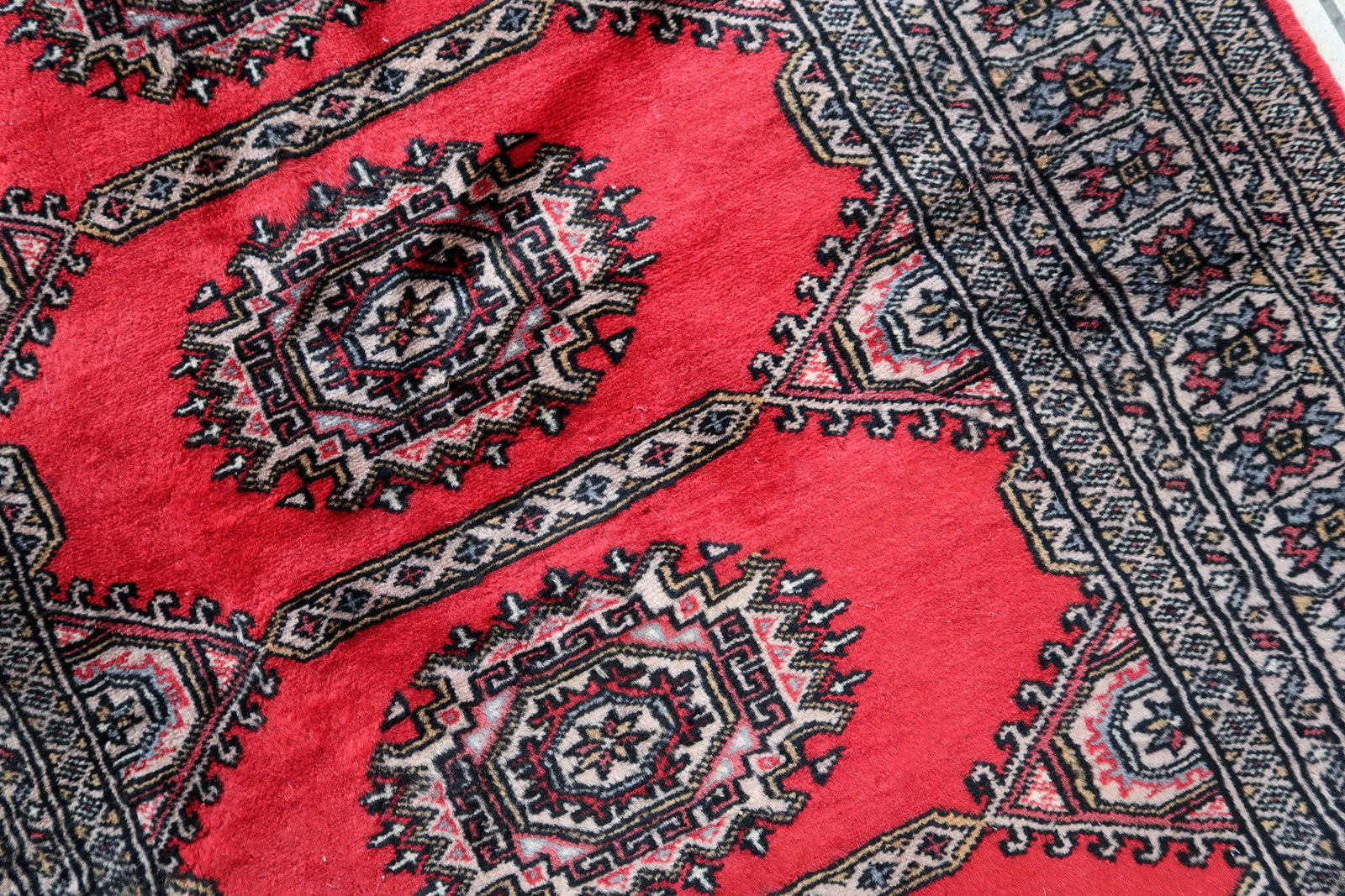 Handmade vintage Uzbek Bukhara rug in red color. The rug has been made in wool in the end of 20th century. It is in original condition, it has some signs of age.