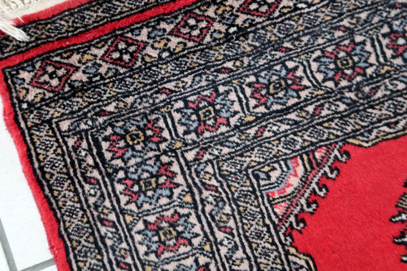 Handmade vintage Uzbek Bukhara rug in red color. The rug has been made in wool in the end of 20th century. It is in original condition, it has some signs of age.