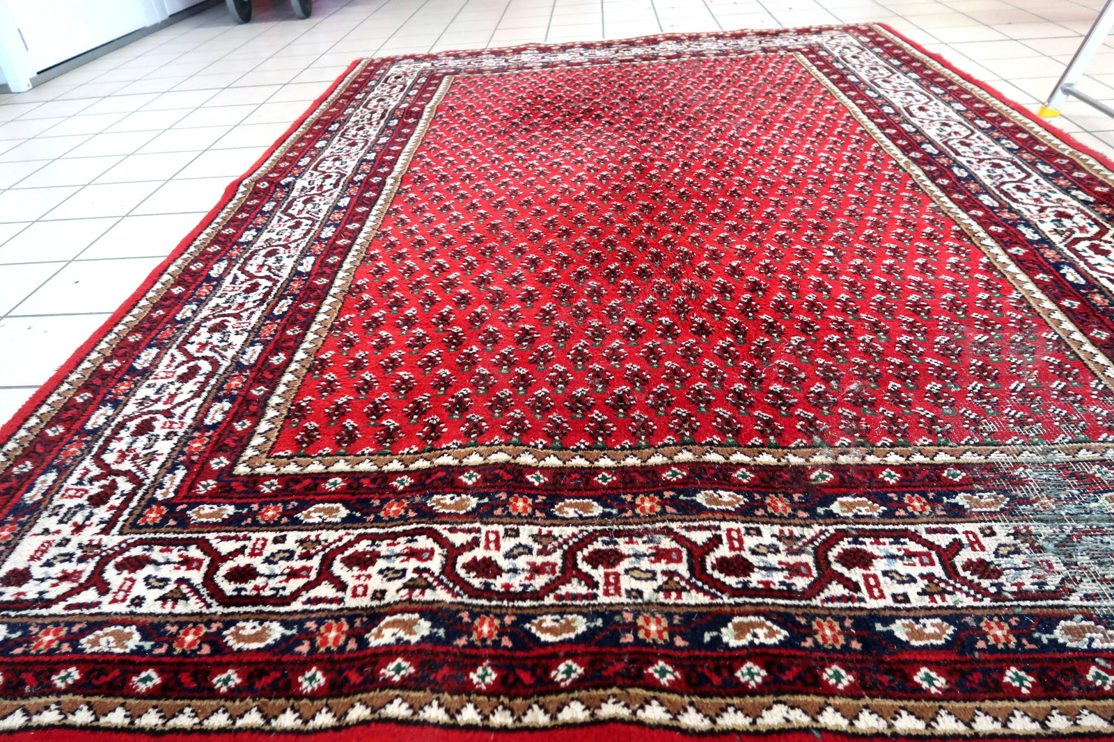 Handmade vintage Indian Seraband rug in original condition, it has some age wear on the one end. The rug has been made in traditional pattern, it is from end of 20th century. The shades of the rug are mostly in red and white. All-over design will bring some modern look to your space. All dyes on this rug are natural. This is the type of rug woven in India to compete in the same market as rugs from Persia.