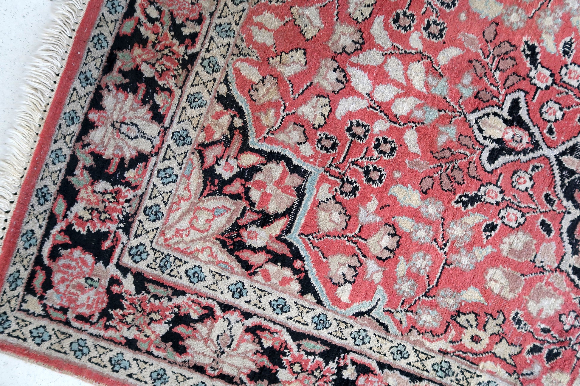 Handmade vintage Persian Tabriz rug made in Kashmir wool. The rug is from the end of 20th century in original good condition. The rug is in traditional medallion design in pink and black colors. Like many recent Tabrizes, this example shows floral figures drawn in a manner suggestive of Safavid art.