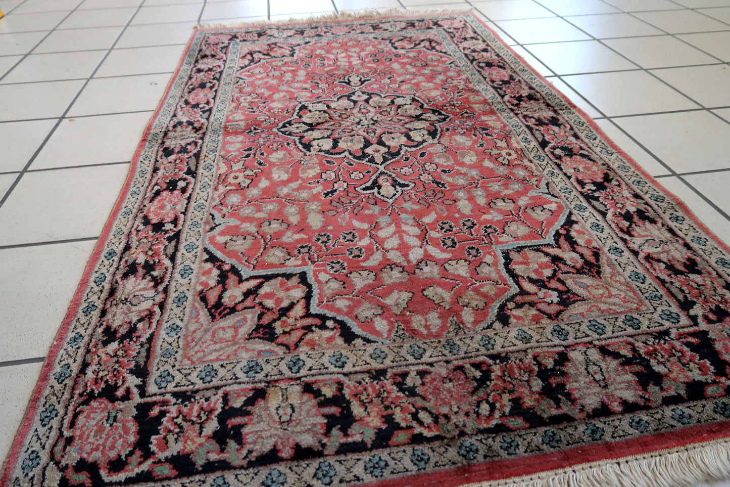 Handmade vintage Persian Tabriz rug made in Kashmir wool. The rug is from the end of 20th century in original good condition. The rug is in traditional medallion design in pink and black colors. Like many recent Tabrizes, this example shows floral figures drawn in a manner suggestive of Safavid art.