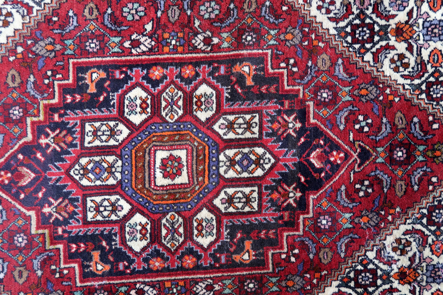 Handmade vintage Persian Bidjar woolen rug. The rug is from the end of 20th century, it is in original good condition. The rug is in traditional design with large medallion in the center. The color combination is white and red.